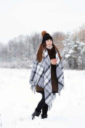 Portrait of a girl in the winter with a candle, in a checkered rug, full heightの写真素材