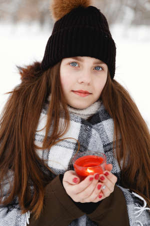 Portrait of a girl in the winter with a candle in a checkered rugの写真素材