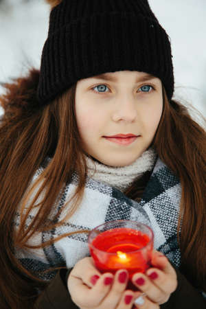 Portrait of a girl in the winter with a candle in a checkered rugの写真素材