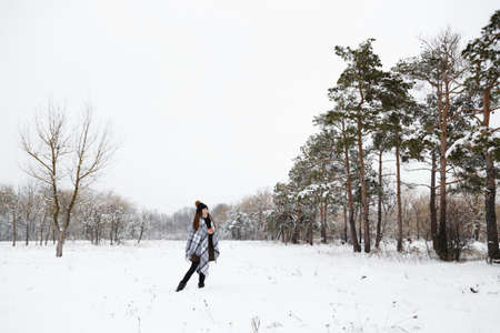 Portrait of a girl in the winter with a candle, in a checkered rug, full heightの写真素材