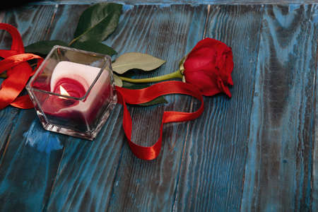 bouquet of red roses, a candle, a heart with a red ribbon on the old blue boardの写真素材