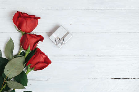 Red roses bouquet and gift box on white wooden background.の写真素材