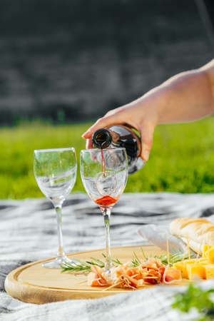 a picnic in nature a light meal under wine, on a wooden background two glasses of red wine, prosciuttoの写真素材