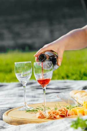 a picnic in nature a light meal under wine, on a wooden background two glasses of red wine, prosciuttoの写真素材