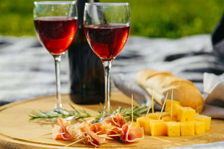 a picnic in nature a light meal under wine, on a wooden background two glasses of red wine, prosciuttoの写真素材