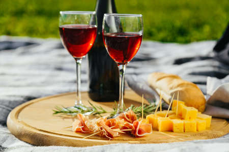 a picnic in nature a light meal under wine, on a wooden background two glasses of red wine, prosciuttoの写真素材