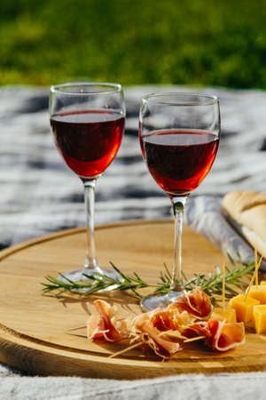 a picnic in nature a light meal under wine, on a wooden background two glasses of red wine, prosciuttoの写真素材