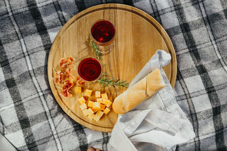 a picnic in nature a light meal under wine, on a wooden background two glasses of red wine, prosciuttoの写真素材