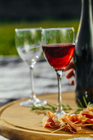 a picnic in nature a light meal under wine, on a wooden background two glasses of red wine, prosciuttoの写真素材