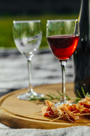 a picnic in nature a light meal under wine, on a wooden background two glasses of red wine, prosciuttoの写真素材