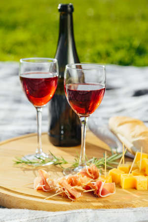 a picnic in nature a light meal under wine, on a wooden background two glasses of red wine, prosciuttoの写真素材