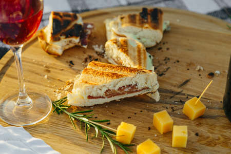 Fresh sandwich with meat and herbs with pieces of cheese and wine in fresh airの写真素材