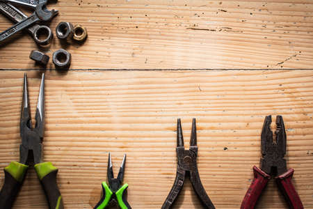 VARIOUS PLIERS AND SCREW WRENCHES LAYING ON A WOODEN TABLE. FOR ADVERTISING SERVICES FOR WORKSHOPS, DIY, GOLD HANDSの写真素材