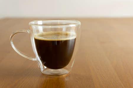 A glass with black coffee on the wooden tableの写真素材