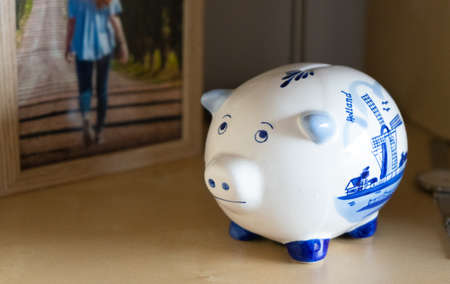 Piggy bank on a shelf with a photo frame in the backgroundの写真素材