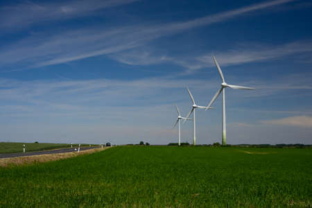 Energy - three wind turbines on green fields against a blue sky.の写真素材