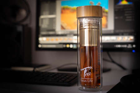 Tea bottle standing on the desk at the computer, work photographerの写真素材