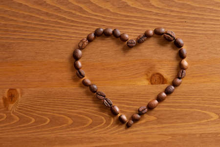 Heart formed by coffee beans on woodの写真素材