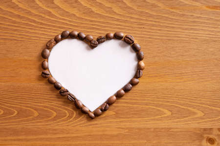 Heart formed by coffee beans on woodの写真素材