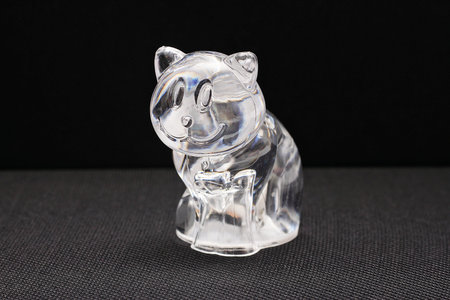 Decorative toy souvenir to decorate glass cat on a black background.