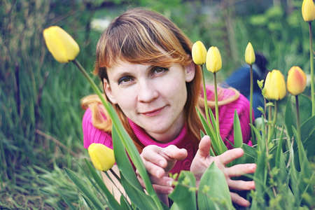 Beautiful woman among yellow tulips in the spring.の写真素材