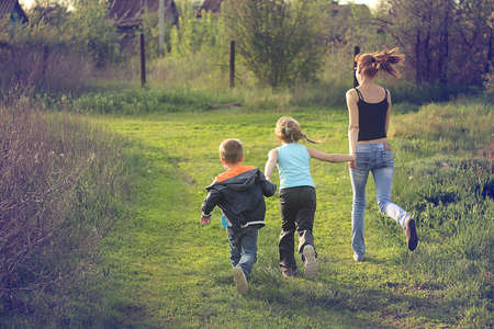 Young woman, girl and boy holding hands jogging in the countryside.の写真素材