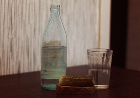 A retro composition consisting of a bottle of vodka, a glass and a pickled cucumber with bread.の写真素材