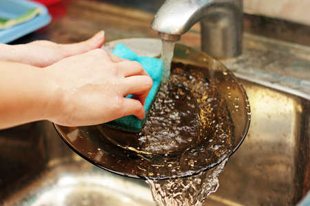 The woman washes plate by soft lip for utensils on the kitchen.の写真素材