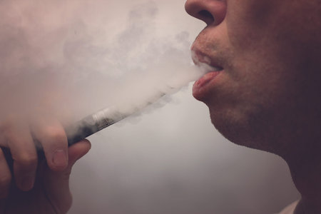 A man smokes an electronic cigarette releasing a huge amount .