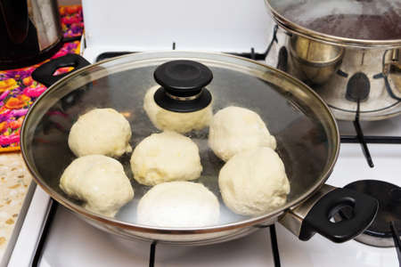 Unprepared pies in a pan with a glass lid before frying.の写真素材
