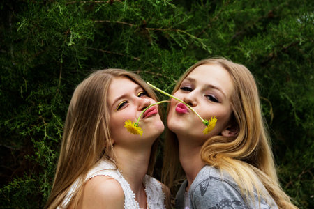 Two cute and beautiful teen girls show grimaces on their faces.の写真素材