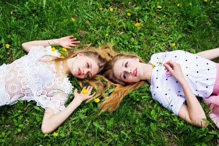 Two girlfriends of the schoolgirl have a rest on the green grass.の写真素材