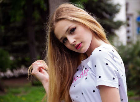 Portrait of a cute russian blonde girl in a city park.の写真素材