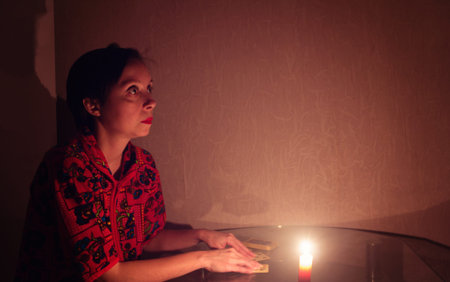 Woman wondering on playing cards by candlelight.