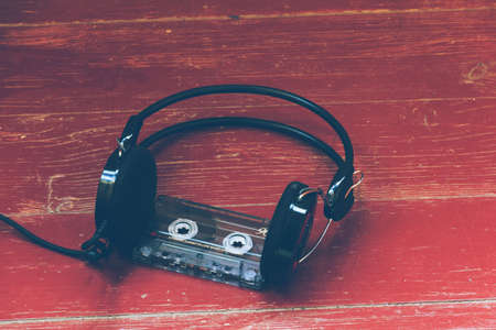 Cassette tape and headphones on a wooden surface. Photo in retro and vintage style.の写真素材