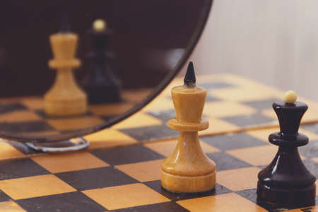 Two chess pieces king and queen on the chessboard and their reflection in the mirror.の写真素材
