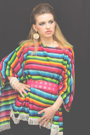 Studio waist portrait of a girl in a multi-colored striped shirt isolated by a black background.の写真素材