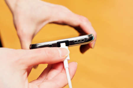 The woman connects the charger to her smartphone.の写真素材