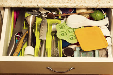 A variety of kitchen utensils in an open kitchen drawer.の写真素材