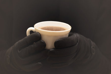 A woman in black leather gloves holds a cup of hot chocolate.の写真素材