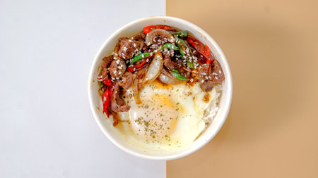 Rice topped with beef and egg and chili on a white backgroundの写真素材