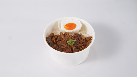 Rice topped with stir-fried pork and egg on white backgroundの写真素材