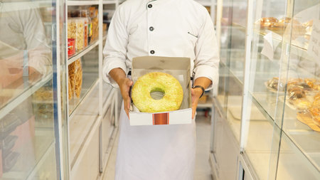 bakery chef holding cake in bakery shop, confectionery conceptの写真素材