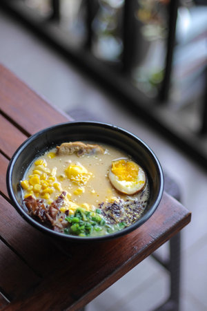 Bowl of miso soup with pork and egg on wooden tableの写真素材