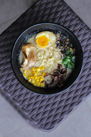 Japanese ramen with egg, rice and vegetables in a black bowlの写真素材