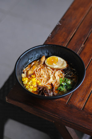 japanese ramen noodle with egg and vegetables in black bowlの写真素材
