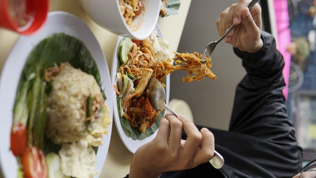 Close up of Asian man eating fried noodle and vegetable in restaurant