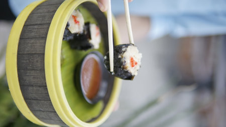 Close-up of a person holding a sushi roll in a restaurantの写真素材