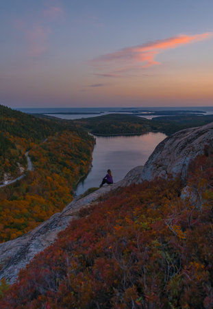 Epic Sunrise Landscape Female Hiker in Purple Shirt Sitting On Rock Edge. Acadia National Park Adventure Inspiring Nature Photography Wideの写真素材