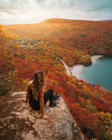 Epic Autumn Scenic Viewpoint Adventure Hiking Girl Sits On Edge of Mountain Overlooking Panoramic...